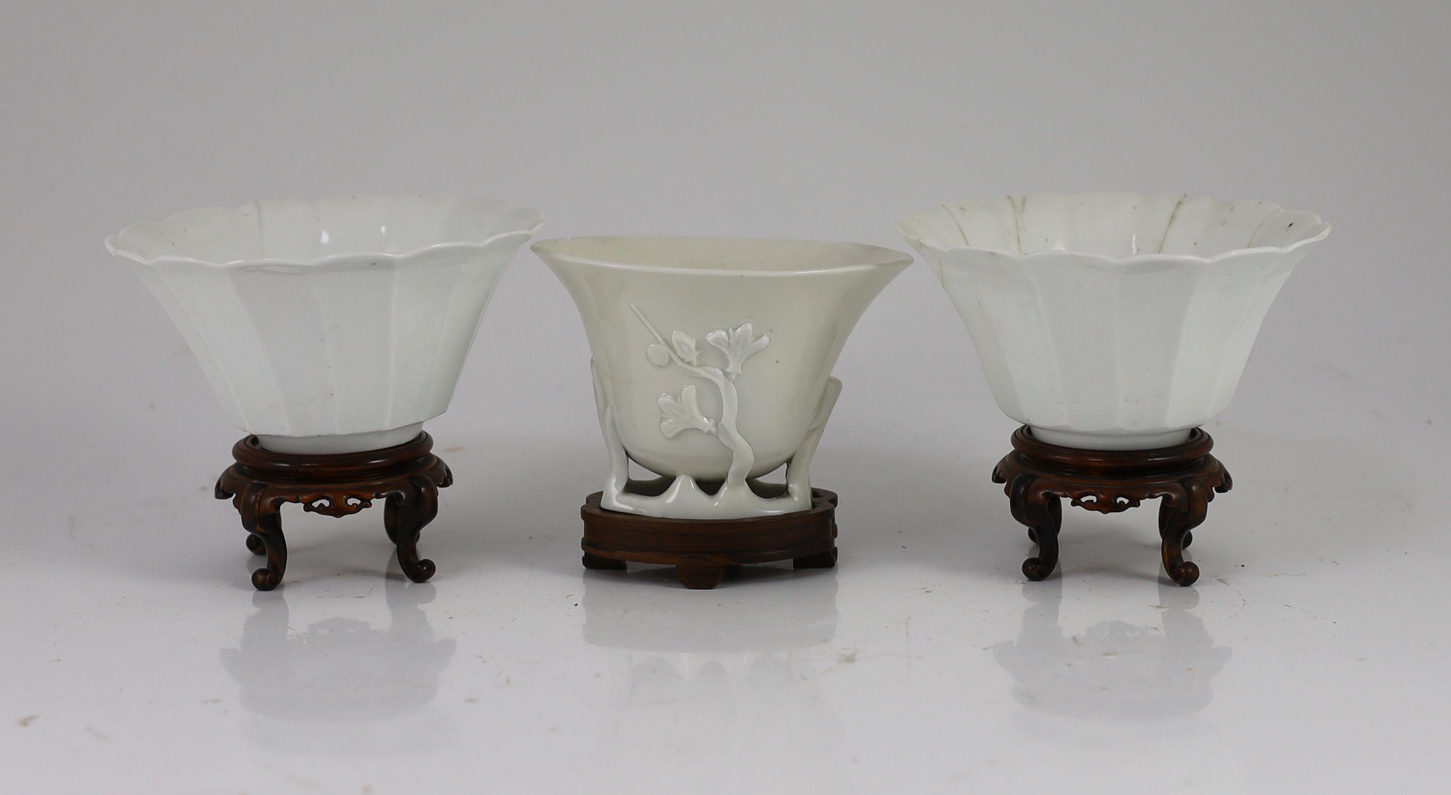 A pair of Chinese blanc-de-chine fluted bowls and a similar libation cup, Dehua kilns, 17th century, 6.5cm high & 7.5cm wood stands, damage